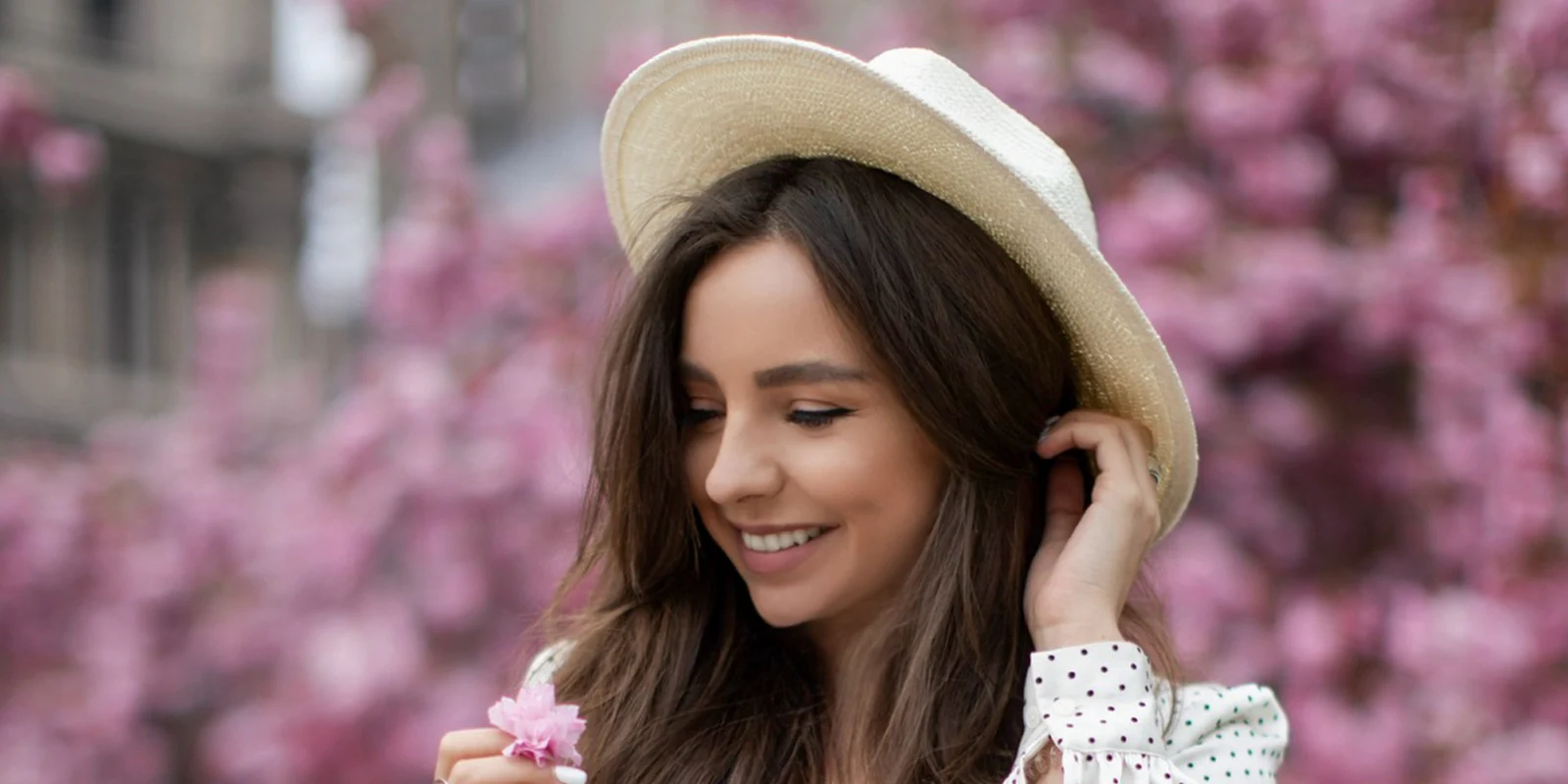 Portrait in a straw hat among cherry blossoms