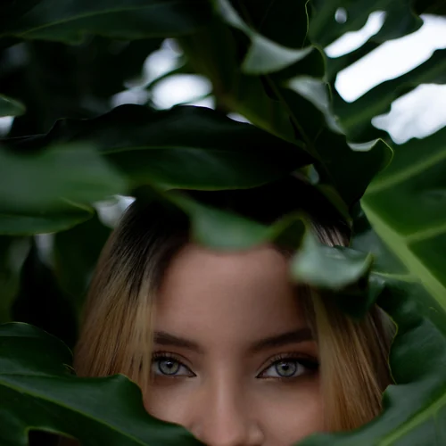 Portrait of a woman framed by large green leaves